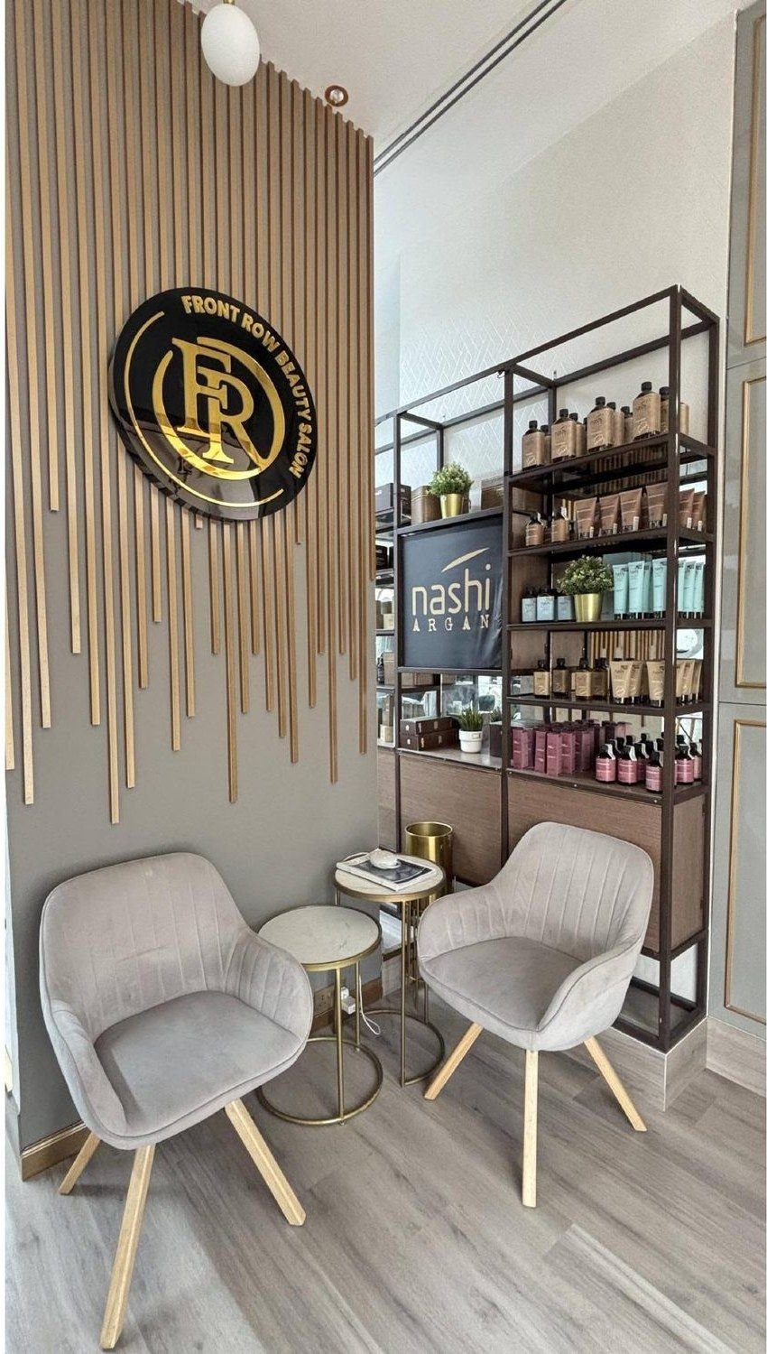 Product display wall and seating at Front Row Beauty Salon, with the salon crest on the wall